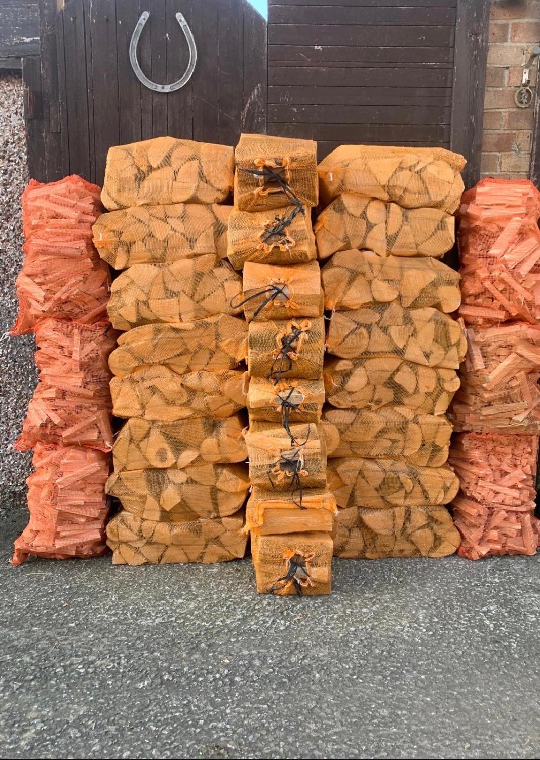Netted sacks of firewood stacked in front of a wooden garden gate