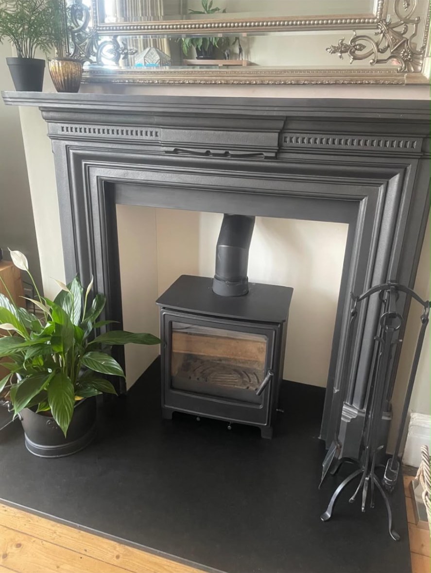 Black wood burner on a slate hearth inside a classic cast-iron fireplace surround