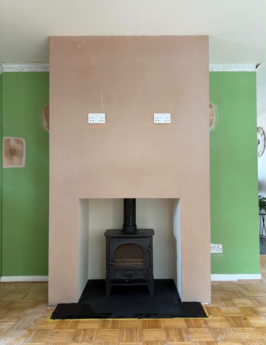 Cast-iron stove on a slate hearth in a newly built, freshly plastered chimney breast