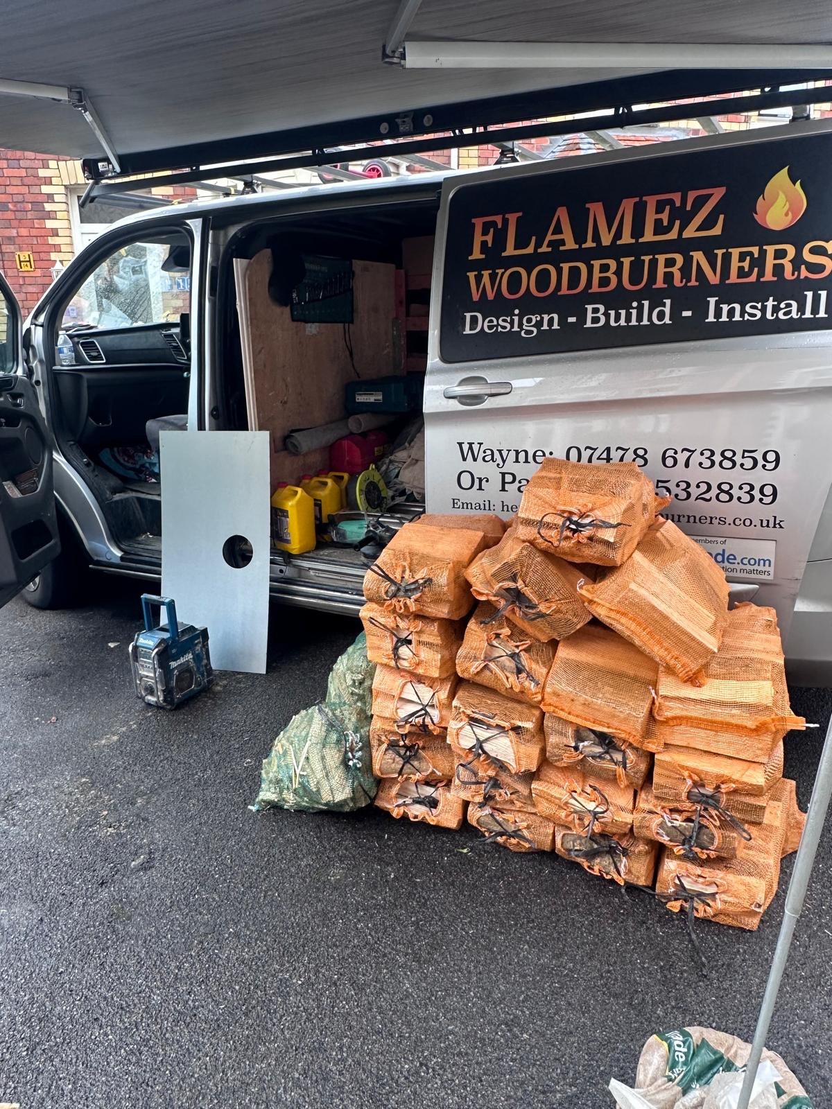 Netted sacks of seasoned logs stacked beside the Flamez Woodburners delivery van