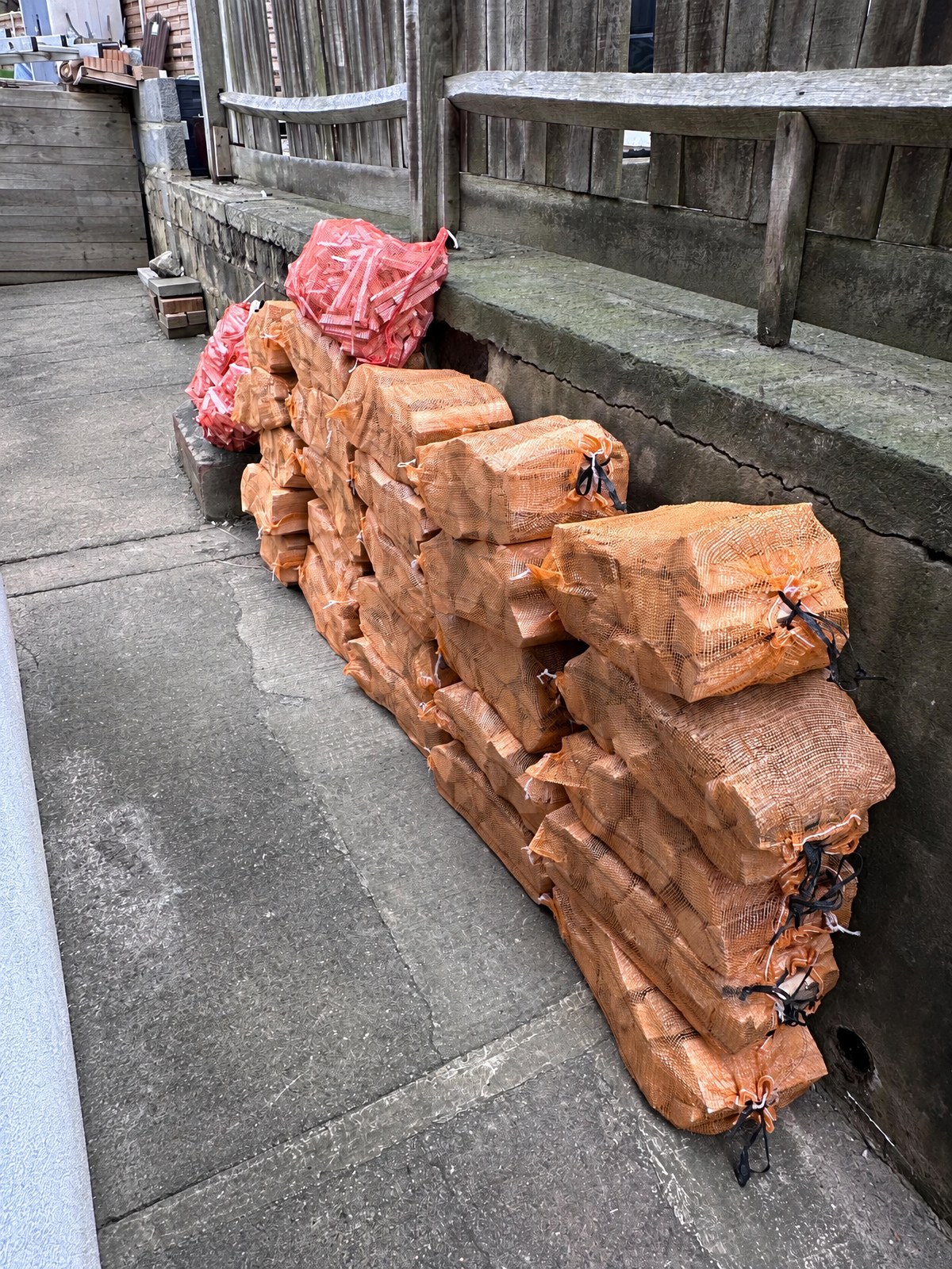 Delivered firewood in netted sacks stacked along a garden path