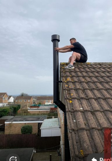 Engineer working at the chimney pot during a flue installation