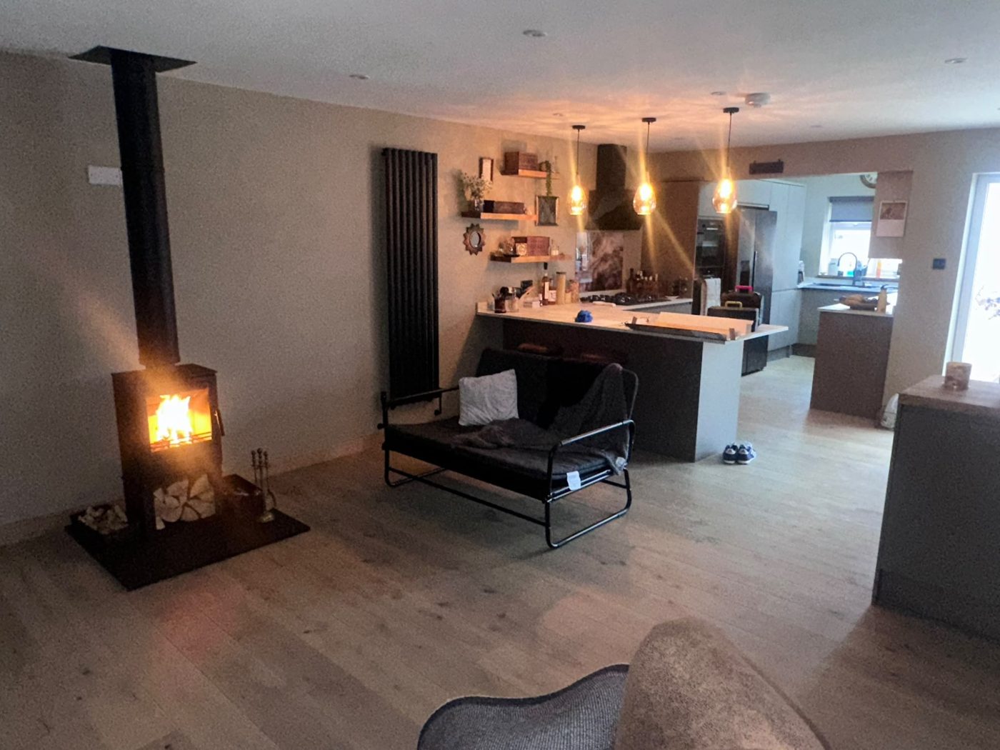 Lit wood burner in an open-plan kitchen and living space