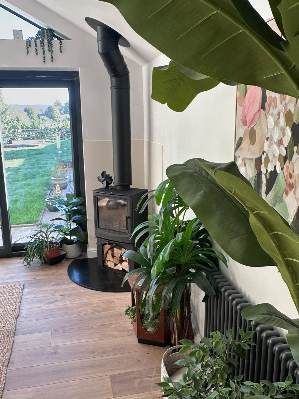 Contemporary stove with log store surrounded by house plants