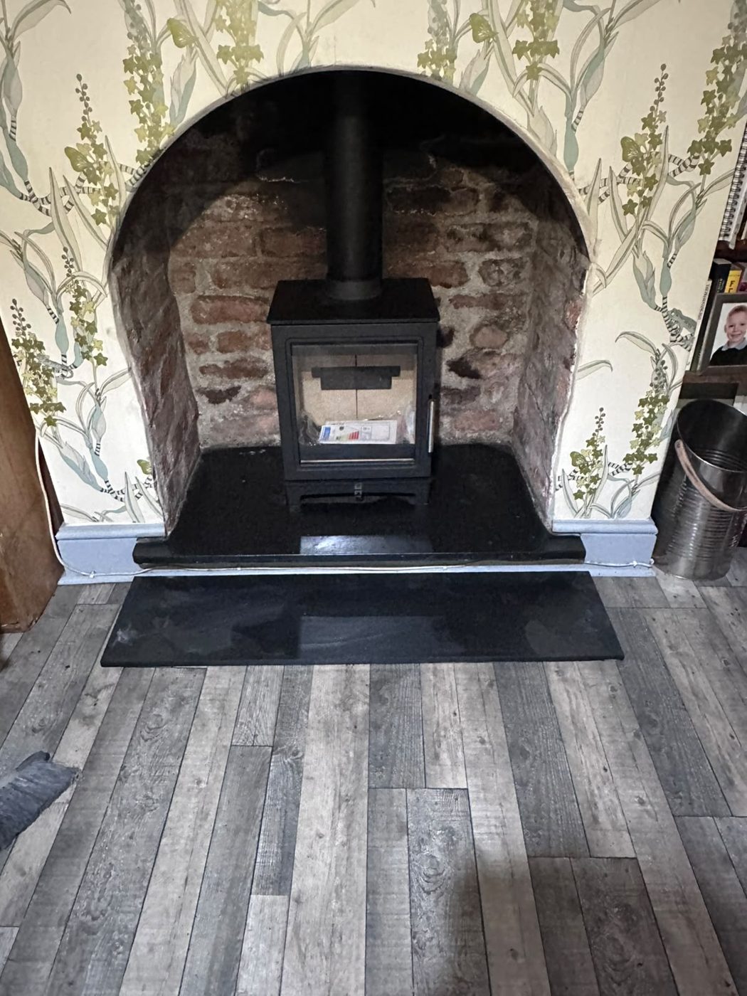 Stove set into an arched brick fireplace with a slate hearth