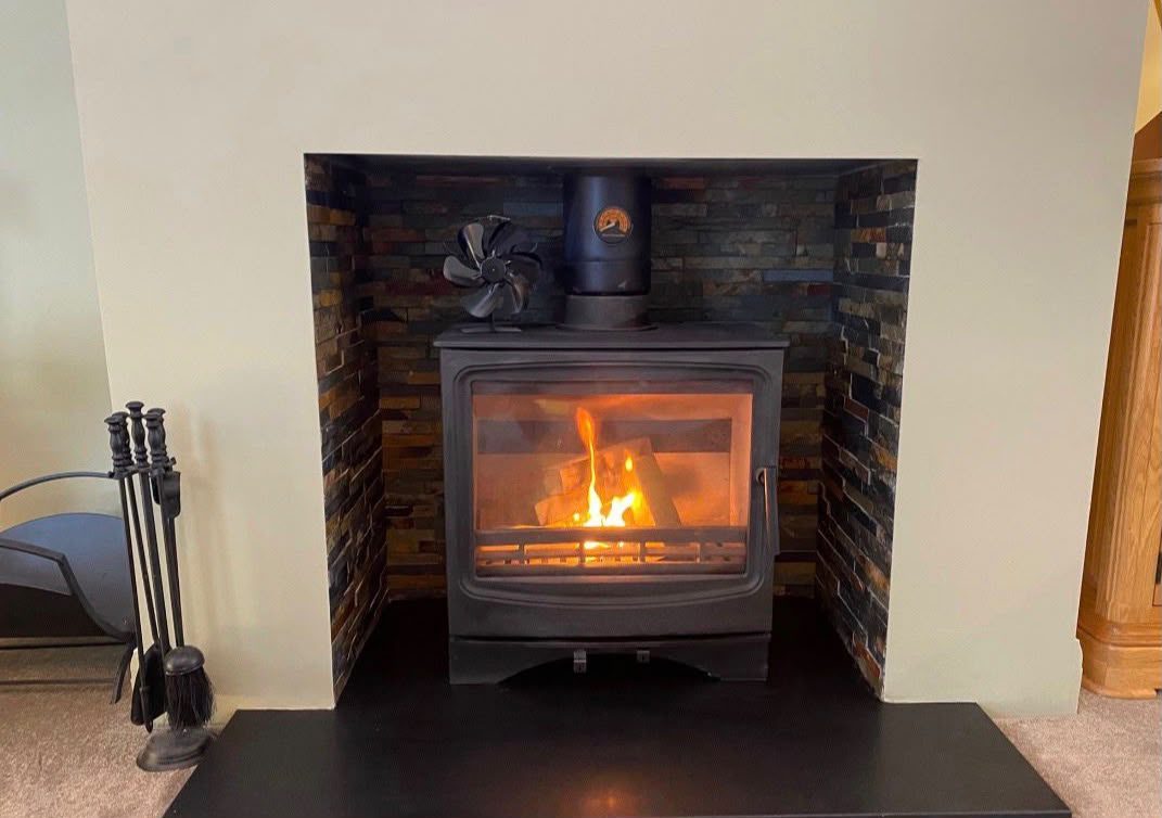 Roaring wood burner in a brick-lined fireplace with black hearth
