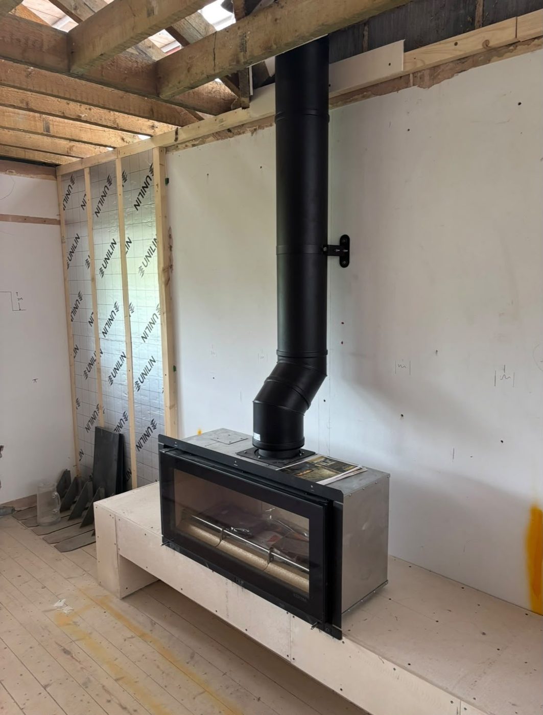 Wide letterbox stove on a raised plinth during installation
