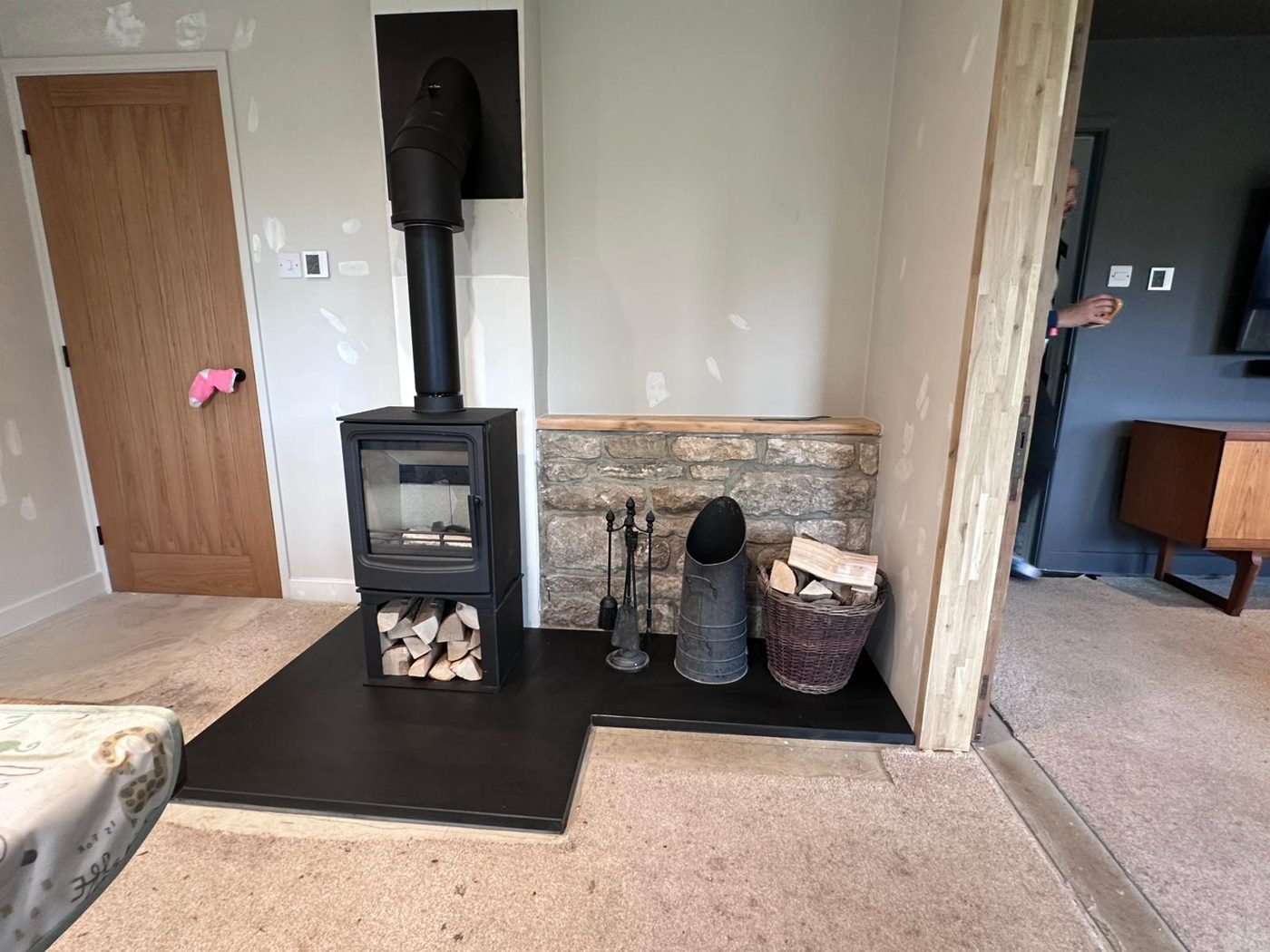 Stove with log storage in a newly built stone-faced alcove