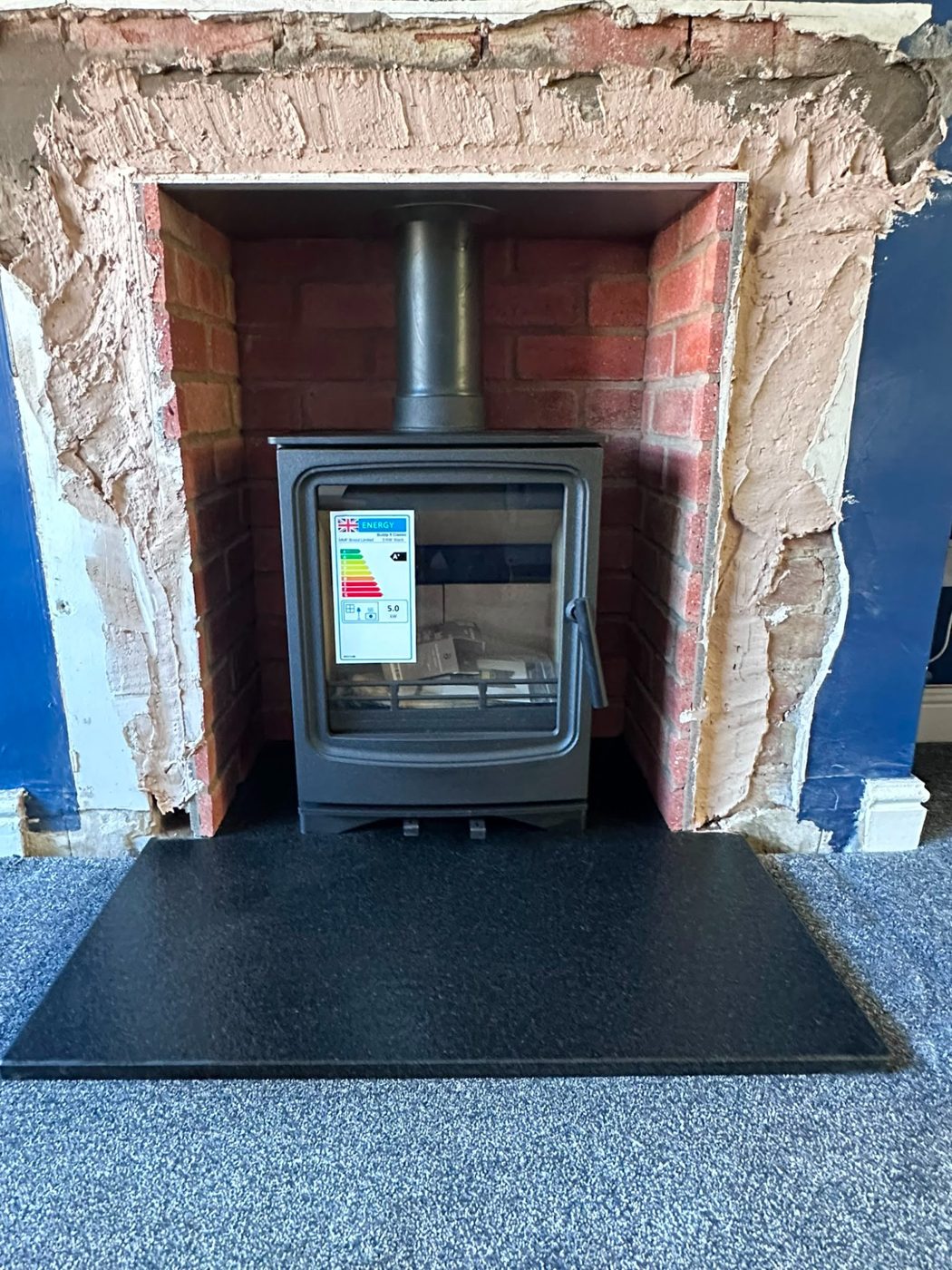 New stove in a brick opening on a black slate hearth