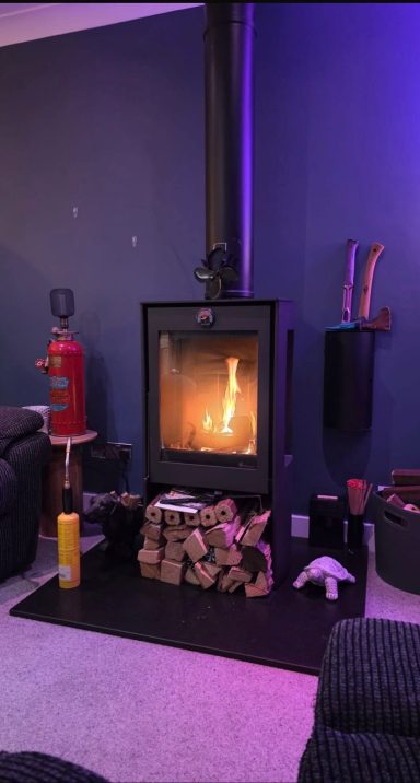Log burner glowing in a colourful living room in the South West